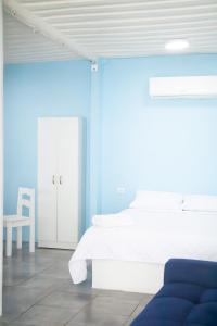 a bedroom with a white bed and a blue wall at Pacífico Cielo Eco Hotel in Atitancito