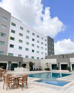 un hôtel avec une piscine, des chaises et un bâtiment dans l'établissement Courtyard by Marriott Villahermosa Tabasco, à Villahermosa