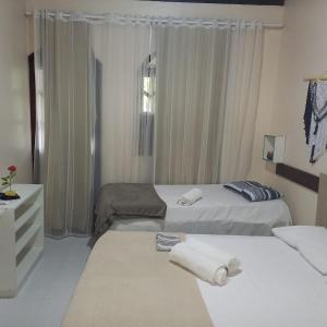 a hotel room with two beds and a window at Suítes Viver Bahia Morro Sao Paulo in Morro de São Paulo