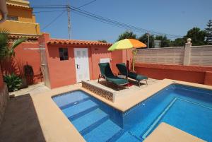 a pool with a chair and an umbrella next to a house at Holidayhome Melodia in Denia
