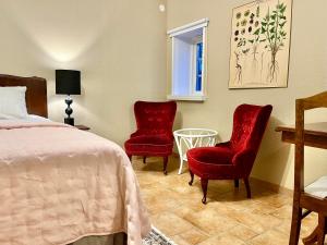 um quarto com duas cadeiras vermelhas e uma cama em Sydkustens at Lillehem em Skivarp
