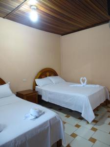Habitación con 2 camas y ropa de cama blanca. en Hostal Ucayali en Tingo María