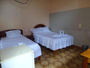Habitación con 2 camas y sábanas blancas. en Hostal Ucayali en Tingo María