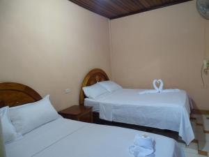 Habitación de hotel con 2 camas con sábanas blancas en Hostal Ucayali en Tingo María