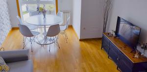 a living room with a white table and a tv at Apartamento Buen Camino in O Pedrouzo