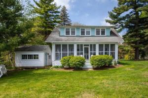 a white house with a blue roof and a yard at Waterfront Cottages in Lexington Vacation Homes in Lexington