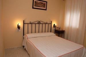 uma cama num quarto com duas luzes na parede em Hotel Don Juan em El Coronil