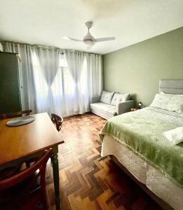 a bedroom with a bed and a table and a couch at Loft aconchegante no Menino Deus in Porto Alegre