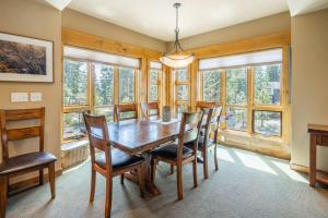 a dining room with a wooden table and chairs and windows at Suncadia Trailhead 1 Pet Friendly Condo 205 in Cle Elum