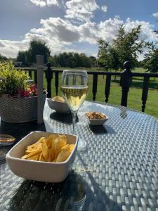 uma mesa com uma taça de batatas fritas e um copo de vinho em Large 2 Bedroom cabin Stunning Views on an 18 Hole golf course em Tydd Saint Giles