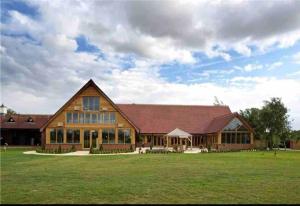 um grande celeiro de madeira com um grande campo de relva em Large 2 Bedroom cabin Stunning Views on an 18 Hole golf course em Tydd Saint Giles