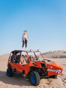 Una mujer parada en la parte superior de un atv naranja en el desierto en Baliyesan, en Ica