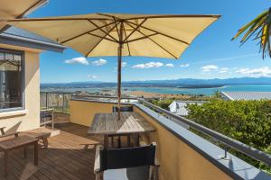 a patio with a table and an umbrella on a balcony at Jacaranda - Views over Tasman Bay in Nelson