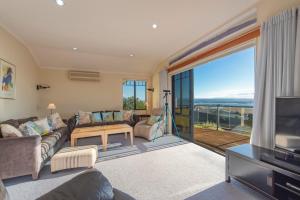 a living room with a couch and a television at Jacaranda - Views over Tasman Bay in Nelson +28 photos