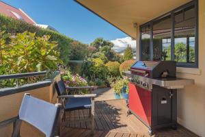 a patio with two chairs and a grill on a porch at Jacaranda - Views over Tasman Bay in Nelson
