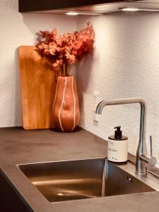um balcão de cozinha com um lavatório e um vaso com flores em The Old Hotel Silkeborg - 1TH em Silkeborg