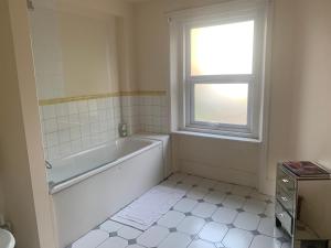 a bathroom with a bath tub and a window at Charming london flat in London