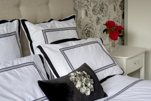 a bed with white pillows and a vase with flowers at Grosvenor House B&B in Cambridge