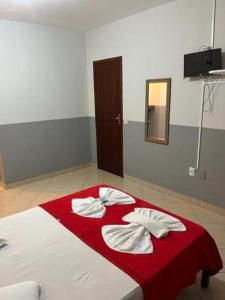 1 dormitorio con 1 cama con manta roja y espejo en Pousada Paraiso Guarapari, en Guarapari