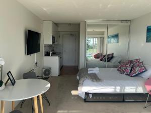 a bedroom with a bed and a table and a kitchen at Dee Why Beach - Studio 29 Surfrider in Deewhy