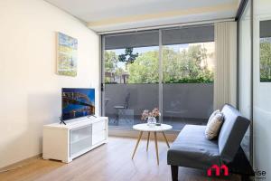a living room with a couch and a tv at MetaWise Burwood Westfield Cozy 2Bed Free Parking VT108 in Sydney