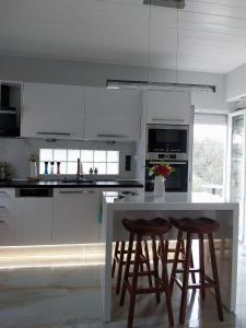 a kitchen with white cabinets and a white island with stools at Apervill Luxury House in Apergátika