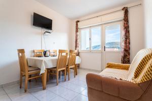 ein Wohnzimmer mit einem Tisch, Stühlen und einem TV in der Unterkunft Apartments with a parking space Vinisce, Trogir - 1165 in Vinišće