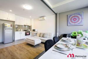 eine Küche und ein Wohnzimmer mit einem Tisch und einem Sofa in der Unterkunft MetaWise Burwood Westfield Cozy 2Bed Free Parking VT109 in Sydney