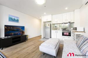 ein Wohnzimmer mit einem Sofa und einer Küche in der Unterkunft MetaWise Burwood Westfield Cozy 2Bed Free Parking VT109 in Sydney