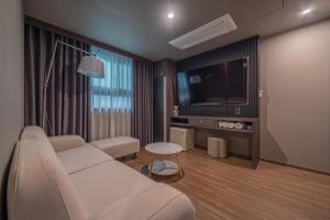 Gyeongju Poverta Hotel في جيونجو: غرفة معيشة مع أريكة بيضاء وتلفزيون