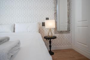 ein Schlafzimmer mit einem Bett mit einer Lampe und einem Spiegel in der Unterkunft Madrid Río Suites in Madrid + 51 Fotos