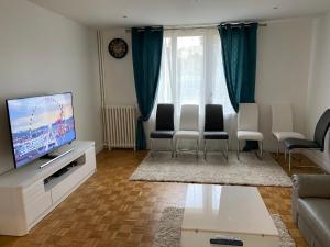 a living room with a flat screen tv and chairs at Résidence Amaya - haut standing au bord de l'Oise in Pontoise