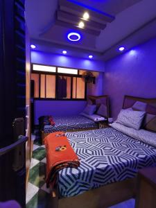 two beds in a room with purple lights at شقة فندقية في بورسعيد Hotel apartment in Port Said in Port Said