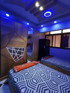 two beds in a room with blue lights at شقة فندقية في بورسعيد Hotel apartment in Port Said in Port Said
