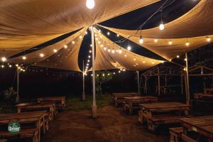 a tent with wooden tables and lights on it at Glamper Grove- Real, Quezon 