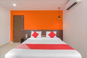 a bedroom with a large bed with an orange wall at OYO Flagship Blooms Residency Near Baiyappanahalli Metro Station in Bangalore