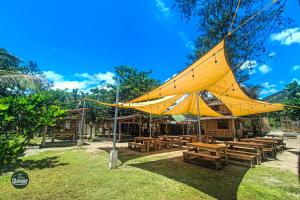 a large yellow tent with wooden tables and benches at Glamper Grove- Real, Quezon 