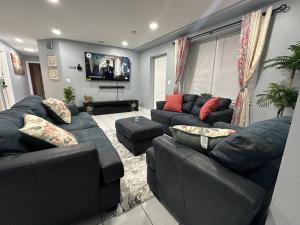 a living room with black couches and a television at Luxury 2-Bedrooms 2-Bathrooms Near NYC/EWR in Newark