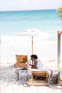 una mujer sentada bajo un paraguas en la playa en Punta Blanca Beach House, en Costa Mujeres