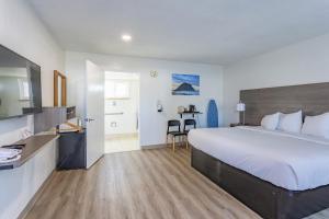 a hotel room with a large bed and a kitchen at Coastal Breeze Inn in Morro Bay
