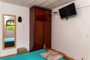 1 dormitorio con 1 cama y TV en la pared en Recanto do majo, en Petrópolis