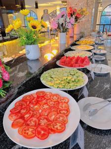 a buffet line with plates of tomatoes and vegetables at Phoenix Hotel H&agrave; Giang in Ha Giang