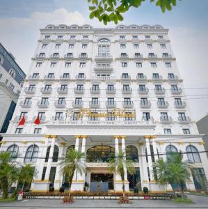 un bâtiment blanc avec des palmiers devant lui dans l'établissement Phoenix Hotel Hà Giang, à Ha Giang