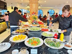 un buffet avec des assiettes de nourriture sur une table dans l'établissement Phoenix Hotel Hà Giang, à Ha Giang