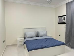 Almansour Laxury Apartement في المدينة المنورة: غرفة نوم بيضاء مع سرير مع لحاف أزرق