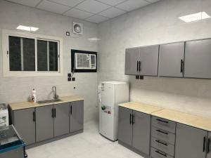 a kitchen with white cabinets and a white refrigerator at Almansour Laxury Apartement in Al Madinah