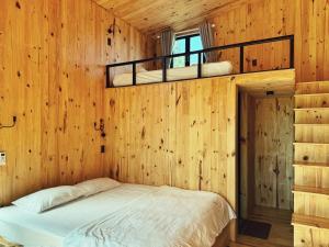 1 dormitorio con 1 cama en una pared de madera en XOM Organic Farm Stay, en Pleiku