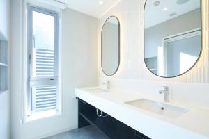 a bathroom with two sinks and a mirror at Hotel Comento Yokohama Kannai in Yokohama