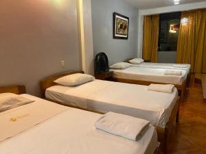 een kamer met 3 bedden met witte lakens bij Hotel Dorado in Moyobamba