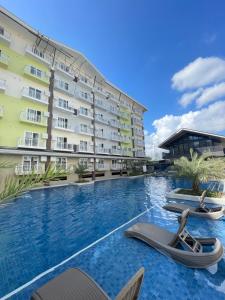 a hotel swimming pool with lounge chairs in front of a building at Travelers Delight Amani Grand Resort Residences 3-5mins from airport in Mactan